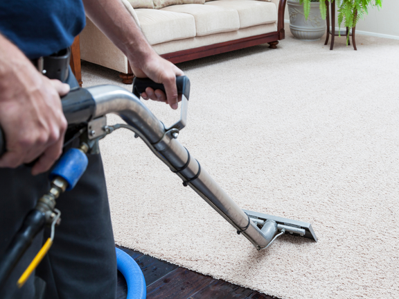 This is a photo of a man with a steam cleaner cleaning a cream carpet works carried out by Purley Carpet Cleaning Solutions.